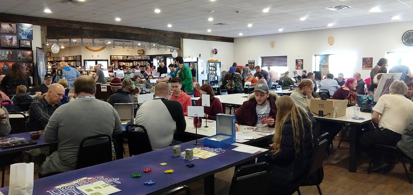 A large room of people play games at tables