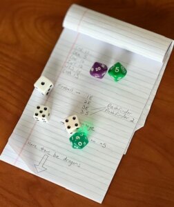 6 dice resting on a notebook with random notes sort of related to RPGs