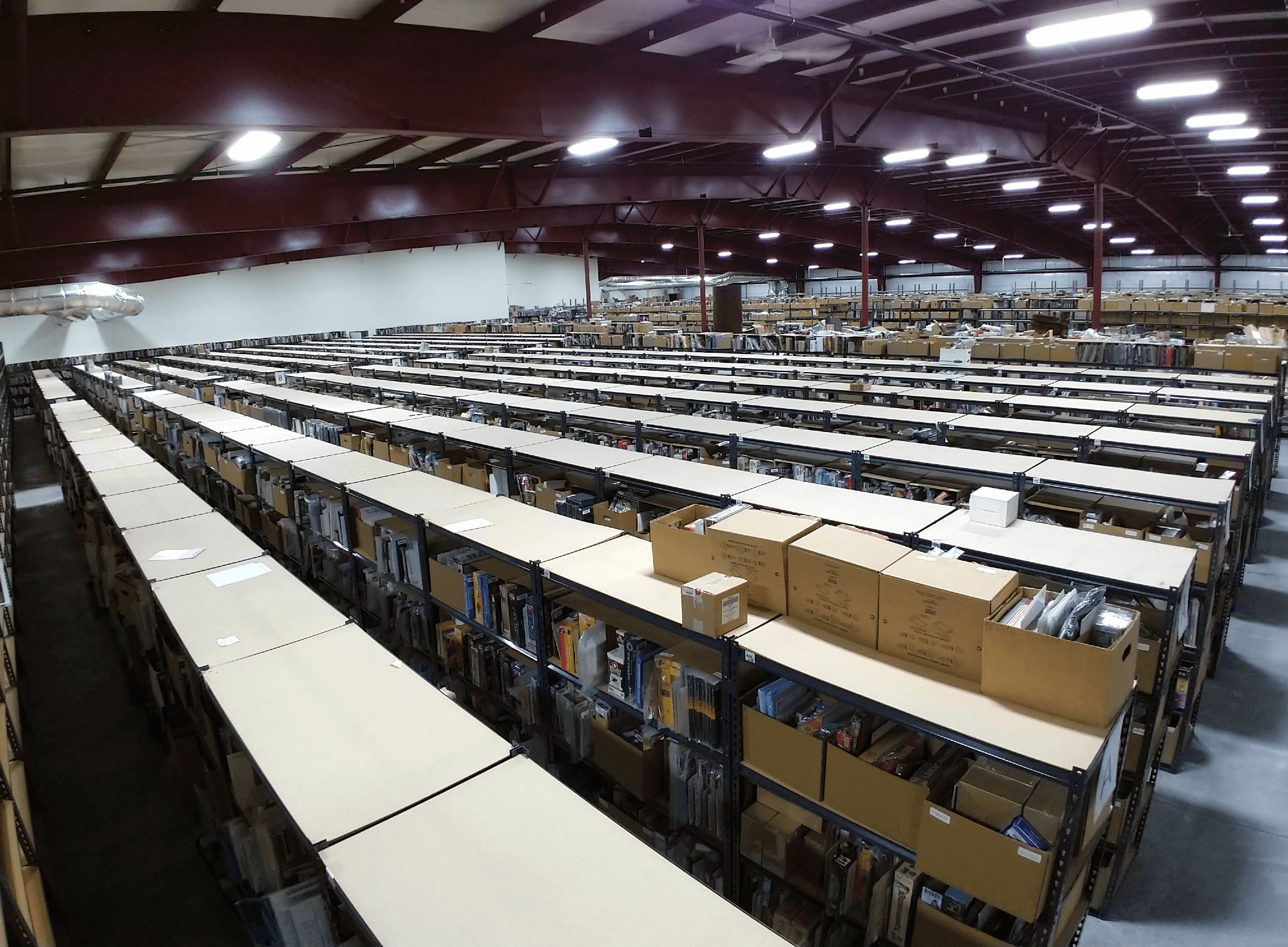 An aerial view from the inside of a large warehouse extending off into the distance with many rows of boxed games on storage shelves