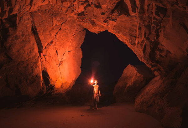 man holding torch inside a cave