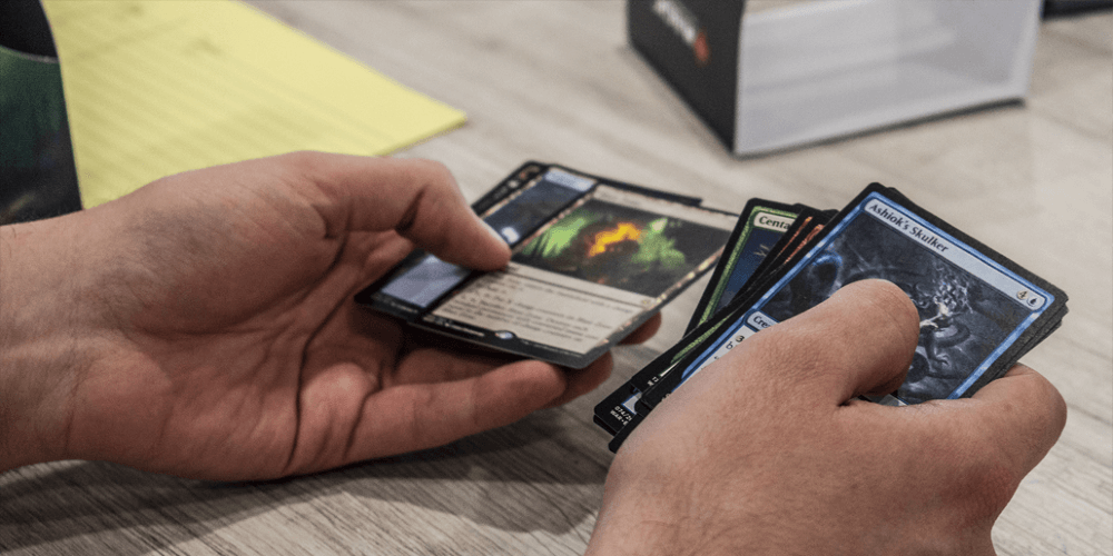 a man's hands sift through Magic the Gathering cards during a draft at Noble Knight Games