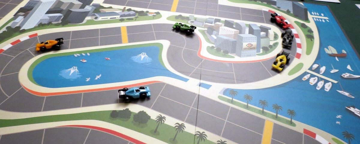 miniature car game pieces on the racetrack gameboard of auto racing board game downforce