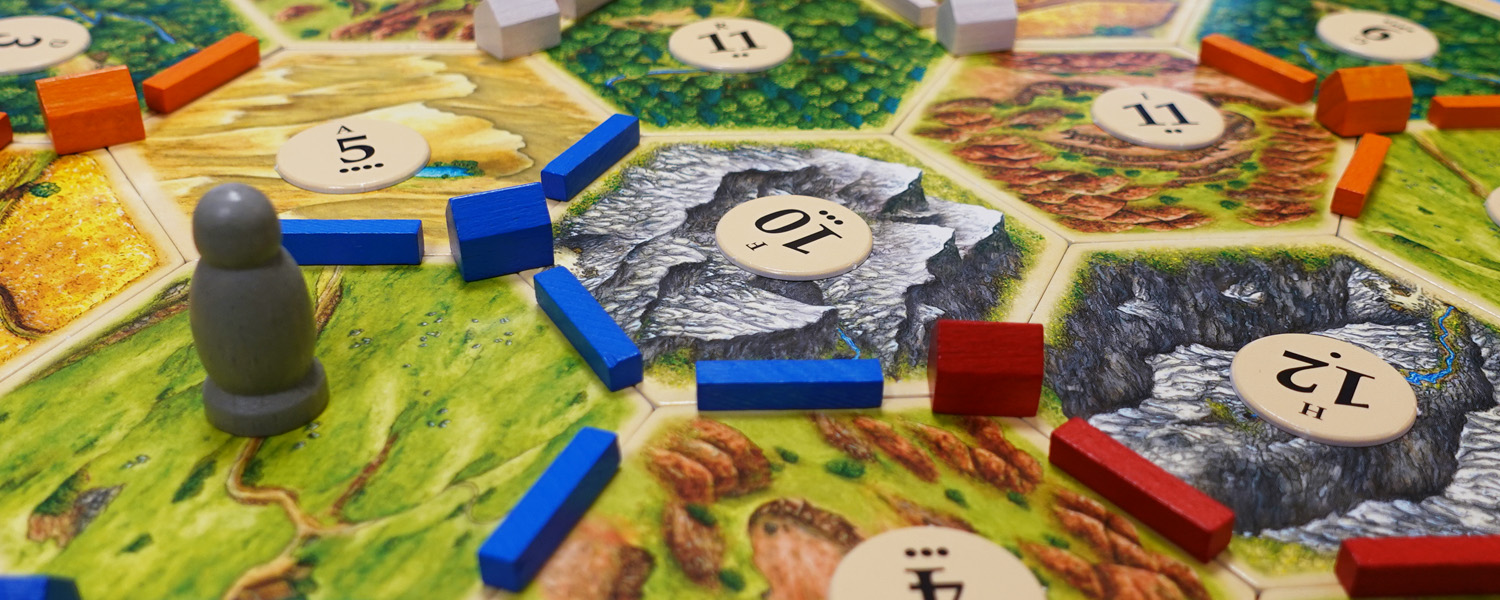 settlers of catan euro games board set up with colored wooden pieces on hexagonal land tiles