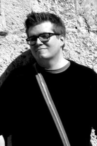 author ben riggs in a black shirt standing in front of a stone wall