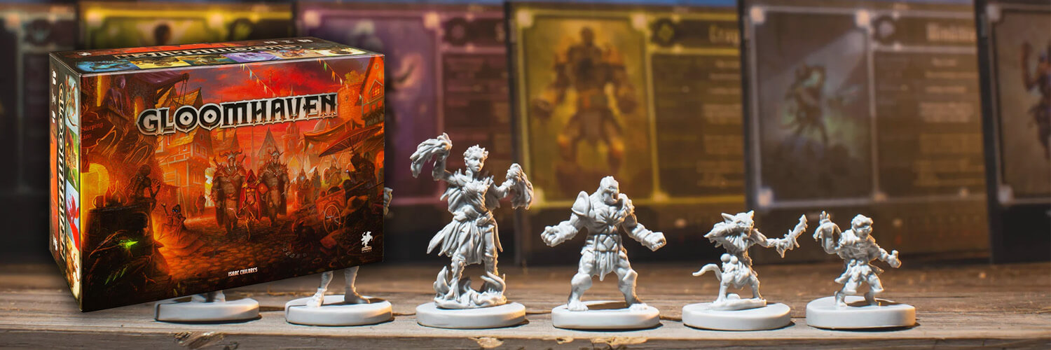 gloomhaven board game box set on top of a photo of some of the miniature figures included in the game