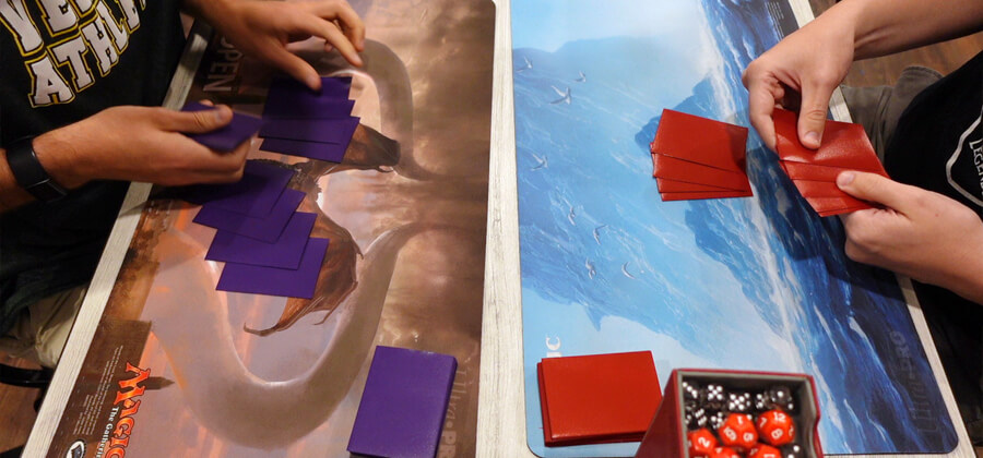 two playmats on a table for a Magic the Gathering game with two sleeved decks being dealt